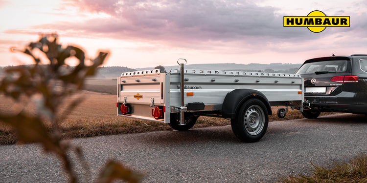 Humbaur Anhänger am VW Golf auf Landstraße bei Sonnenuntergang