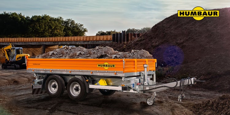 Humbaur Baustellenkipper mit orangefarbener Bordwand, beladen mit Schutt auf Baustelle