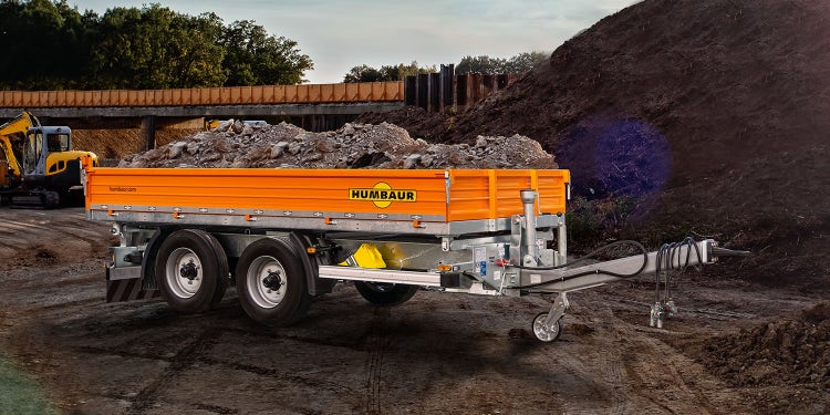 Humbaur Baustellenkipper mit orangefarbener Bordwand, beladen mit Schutt auf Baustelle