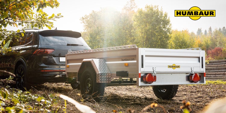 Humbaur Anhänger an VW SUV im Waldgebiet bei Sonnenlicht.